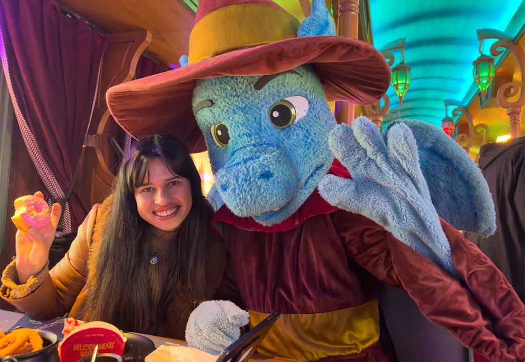 Alessandra do Aventurando Tchê sorrindo ao lado do dragão Hector na Ferrovia Secreta em Gramado