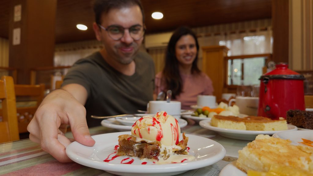 Francisco e Alessandra do Aventurando Tchê bem felizes comendo numa mesa farta no Bela Vista Café Colonial