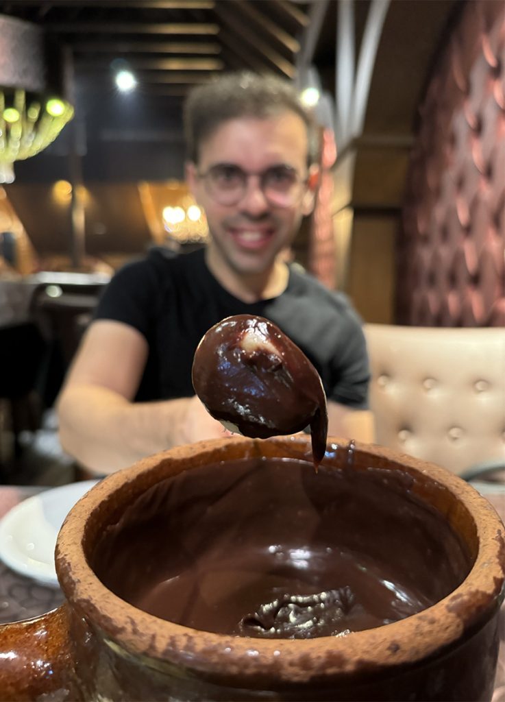 Francisco do Aventurando Tchê mergulhando o morando no fondue de chocolate no restaurante La Famille de Gazon