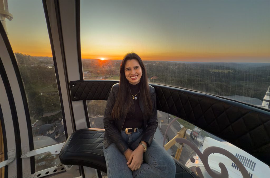 Roda gigante Canela: 5% de desconto no site oficial 4 Alessandra do Aventurando Tchê dentro da cabine da Roda Gigante Canela no pôr do sol