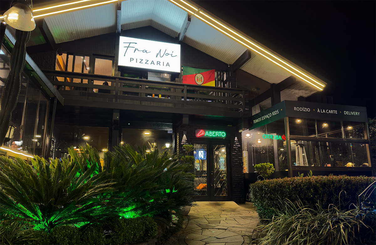 Fachada noturna da Fra Noi Pizzaria em Canela
