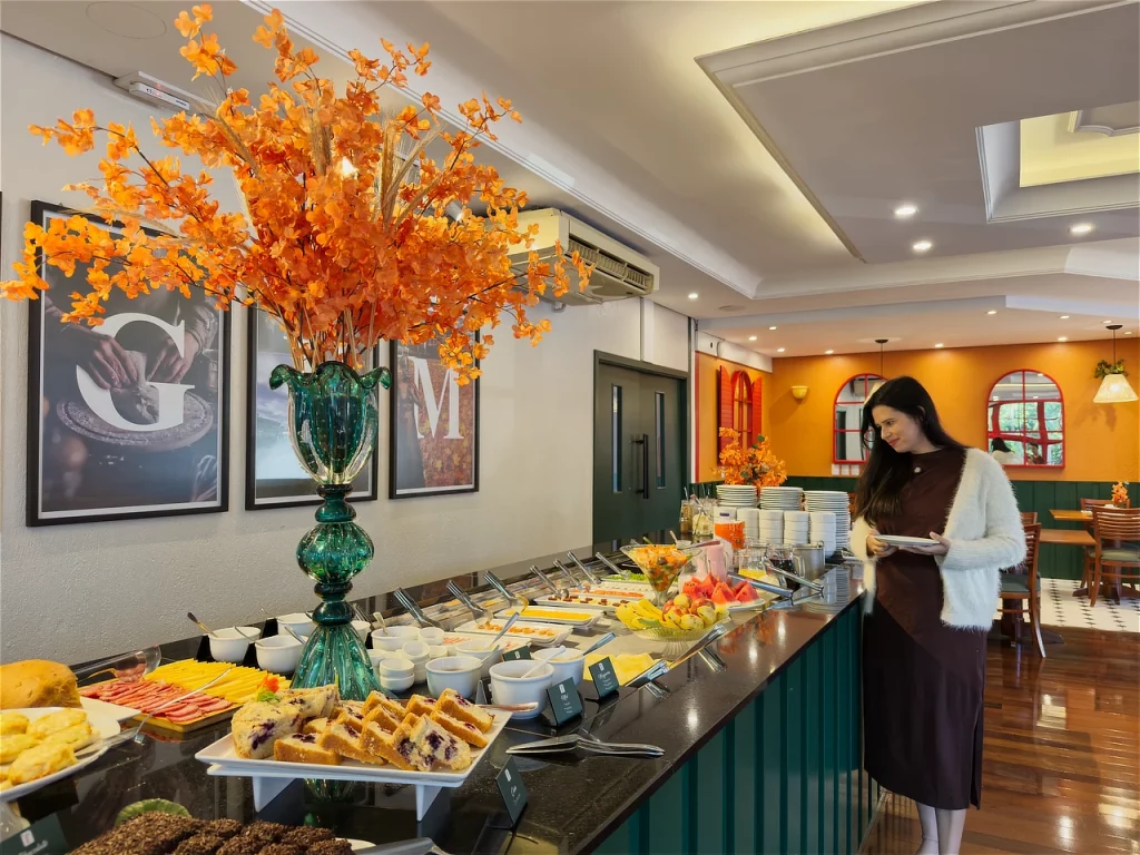 Alessandra do Aventurando Tchê escolhendo o que pegar no buffet do Hotel Fioreze Origem