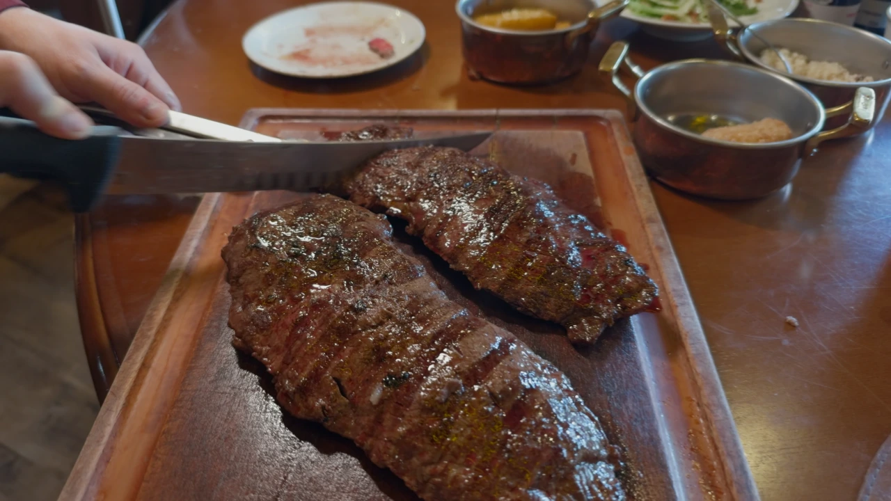 Churrascaria Chama de Fogo Gramado — Corte de carne nobre Black Angus servido e fatiado em tábua de madeira com molho de